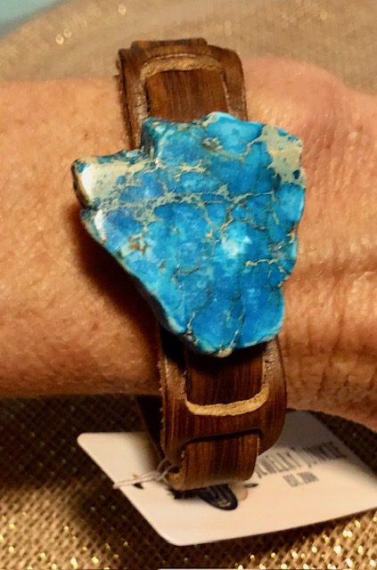 A close up of a wrist watch with a blue stone on it