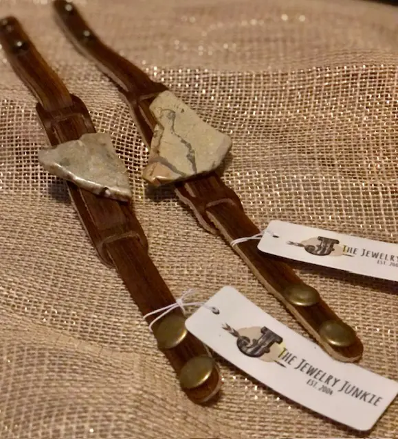 A pair of brown leather suspenders with tags attached.