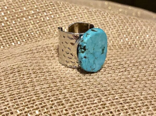 A turquoise stone is on top of a silver ring.