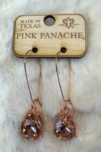 A pair of earrings hanging on a wooden board.