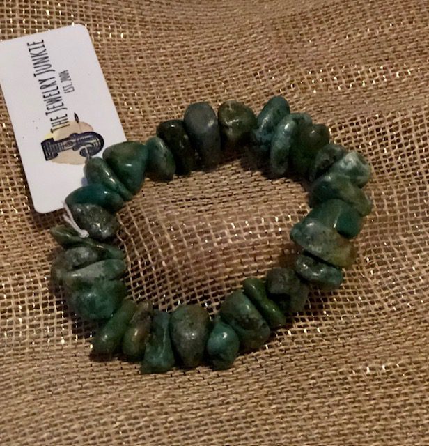 A green bracelet is sitting on the ground.