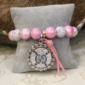 A pink bracelet with a silver and white charm.