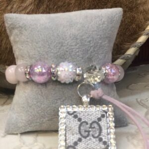 A pink bracelet with a silver square charm.
