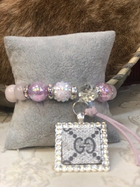 A pink bracelet with a silver square charm.