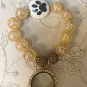A bracelet with a magnifying glass and a paw print on it.