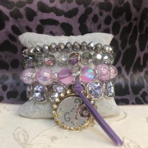 A bracelet with many different beads and a purple bottle cap.