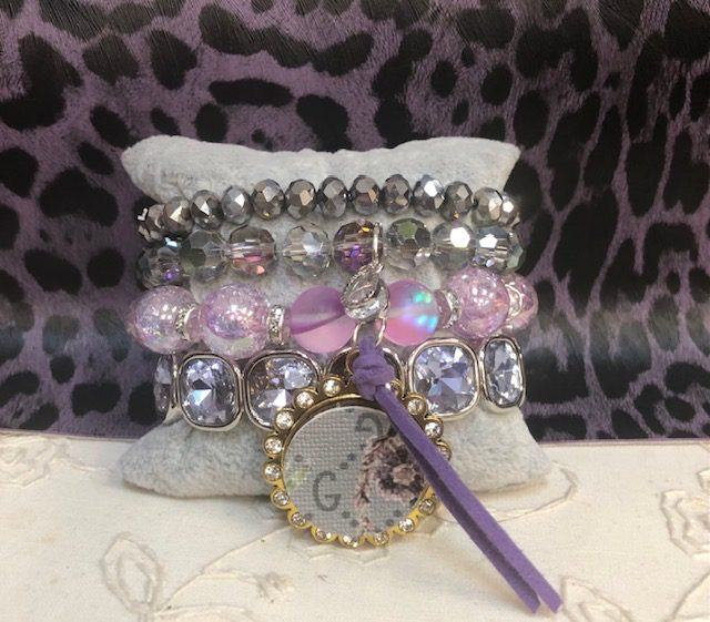 A bracelet with many different beads and a purple bottle cap.