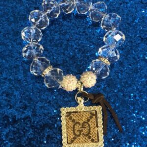 A bracelet with a square shaped charm and beads.
