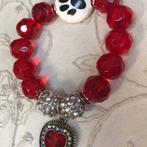 A red bracelet with a heart and paw print charm.