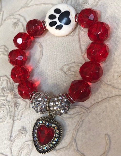 A red bracelet with a heart and paw print charm.