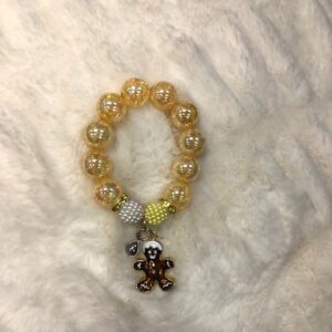 A yellow beaded GIRLS GINGERBREAD BRACELET with a teddy bear charm.