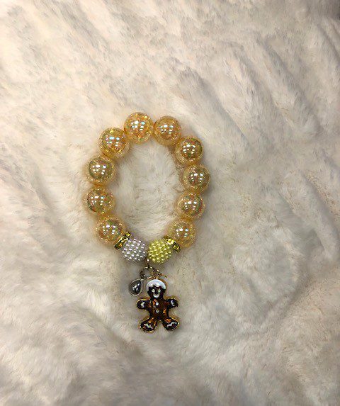 A yellow beaded GIRLS GINGERBREAD BRACELET with a teddy bear charm.
