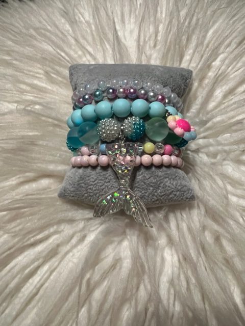 A GIRLS MERMAID STACK set on a pillow.