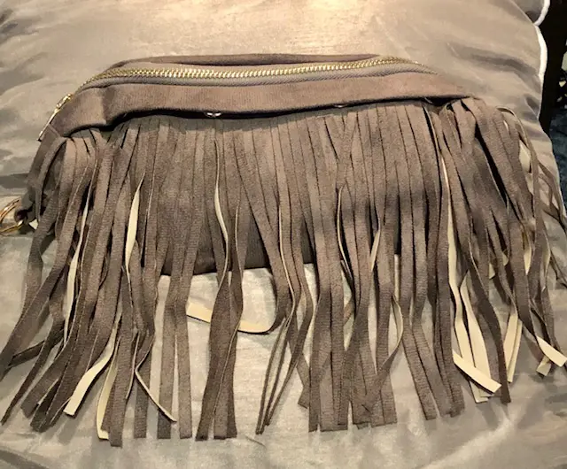 A brown purse with long fringes on top of the bag.