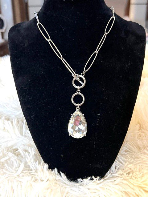 A necklace with a silver chain and a CLEAR TEARDROP NECKLACE pendant.