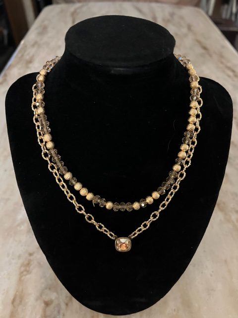 A RHINESTONE NECKLACE with a gold bead and a silver bead.