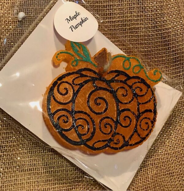 A pumpkin shaped cookie sitting on top of a white plate.