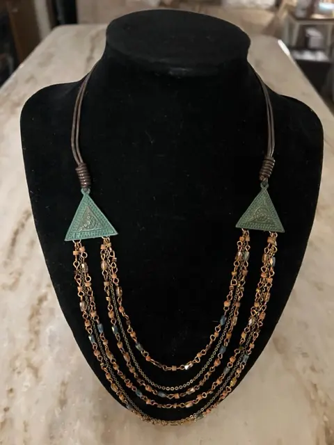 A high strung layered necklace with a triangle on it.