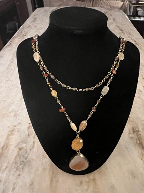 An agate stone metal necklace with an orange stone and gold chain.