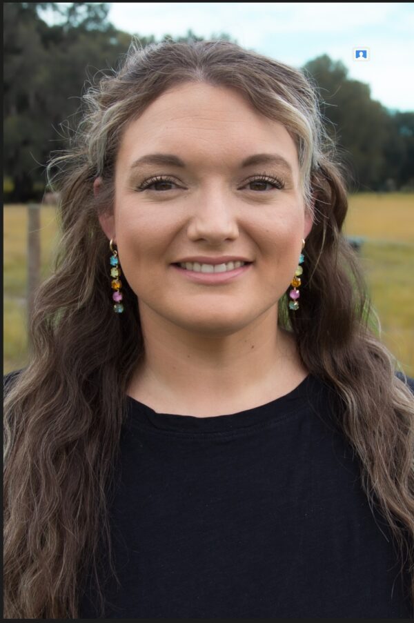 A woman wearing a black shirt and MYRA PASTEL DANGLE EARRINGS.