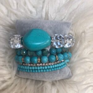 A stack of bracelets on top of a fur pillow.
