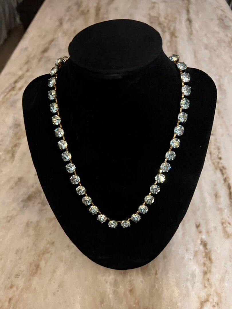 The OAKLAND NECKLACE IN AQUA CHAMPAGNE with blue crystals on a mannequin.