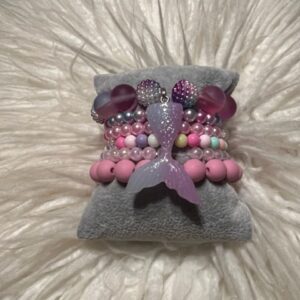 A pillow with a GIRLS MERMAID STACK bracelet on it.