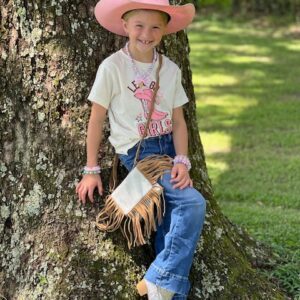 A little girl in a pink cowboy hat leaning against a GIRLS CROSSBODY.