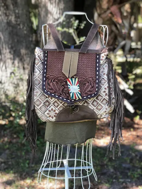 A TOOLED FRINGE BACKPACK with fringes and tassels on a mannequin.