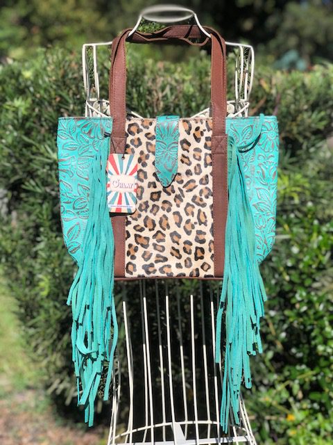 A TURQUOISE FRINGE TOTE with tassels and a leopard print.