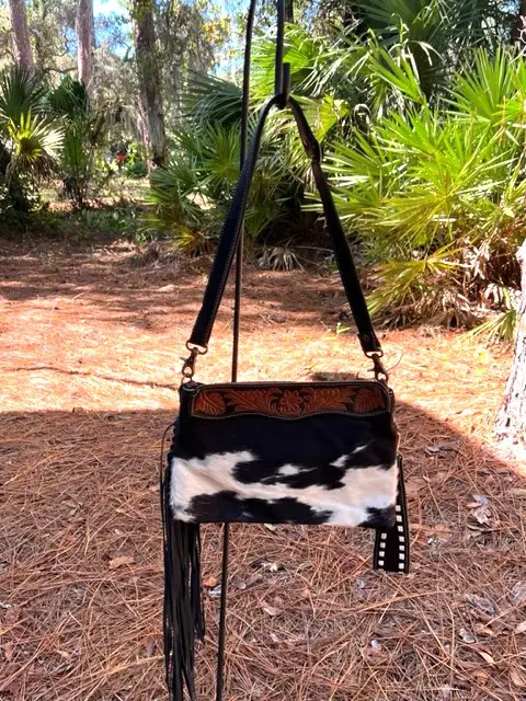 A black and white CISCO LEATHER & HAIRON BAG hanging from a tree.