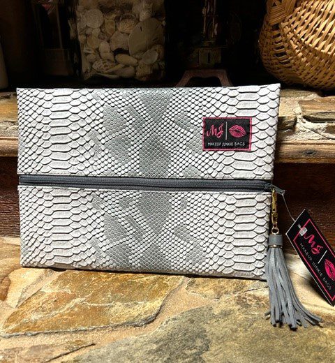 A white python skin SHADOW MAKEUP BAG with a tassel.