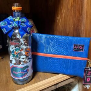 An ORANGE AND BLUE SPIRIT MAKEUP BAG with a gator on it sits on a shelf.