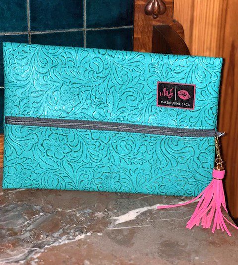 A TURQUOISE DREAM MAKEUP BAG with a pink tassel.