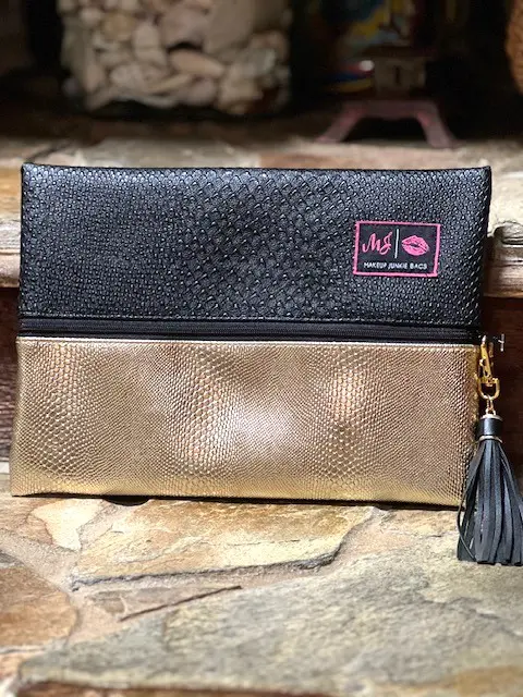 A black and TWO-FACED GOLD SERPENT clutch with a tassel.