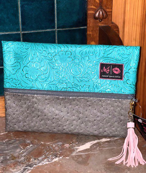A Two-Faced Turquoise Dream clutch with a tassel on it.