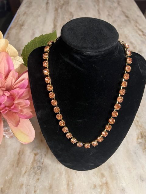 The OAKLAND NECKLACE IN ROSALINE with orange beads is on a mannequin.