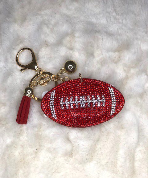 A RED CRYSTAL FOOTBALL KEYCHAIN with a tassel on it.
